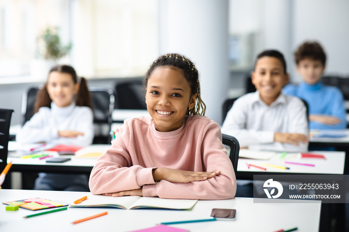 Portrait of small black girl sitting at desk in classroom