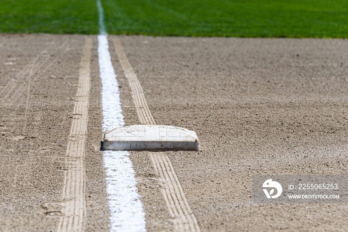 Close up of freshly chalked baseline, with base plate, dirt and grass, empty baseball field on a sun