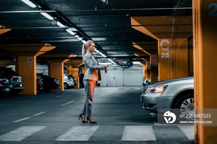 Businesswoman unlocking car in underground parking.