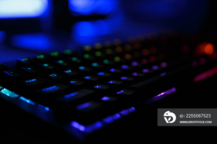 工作场所的特写照片，电脑的led彩虹背光游戏键盘，躺在桌子上