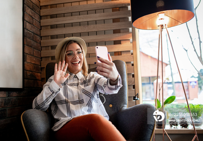 一名年轻女子坐在咖啡店里用智能手机打视频电话。
