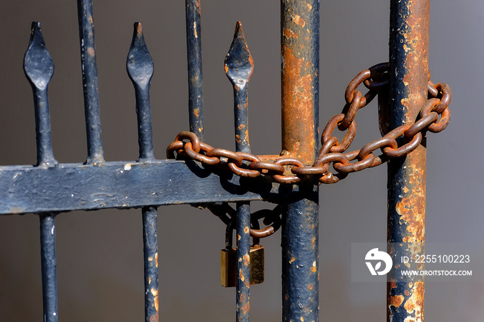 Rusty chain and key locked on an old gate rails