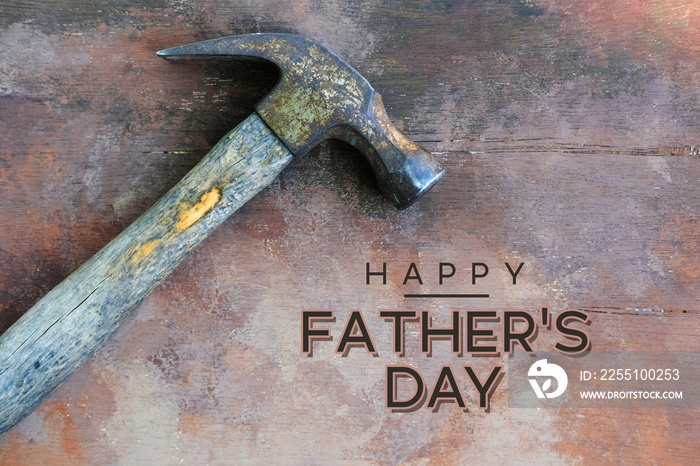 Old hammer tool isolated on wood background for Father’s Day graphic sign.