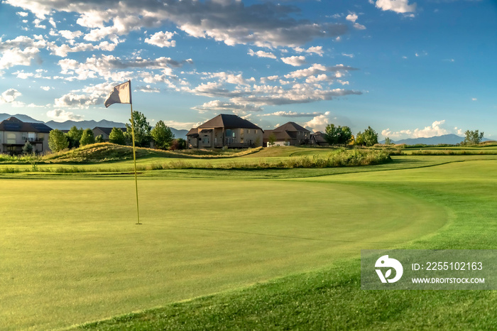 Flagstick on the fairway of a golf course with houses in the background