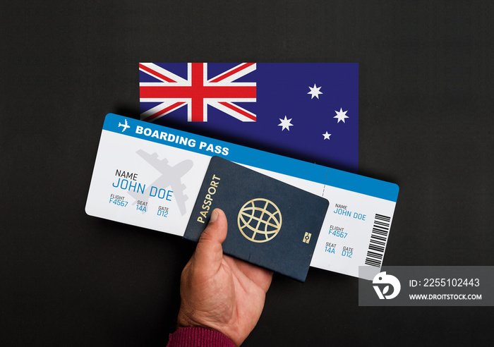 Hand holds passport and boarding pass with flag of Australia