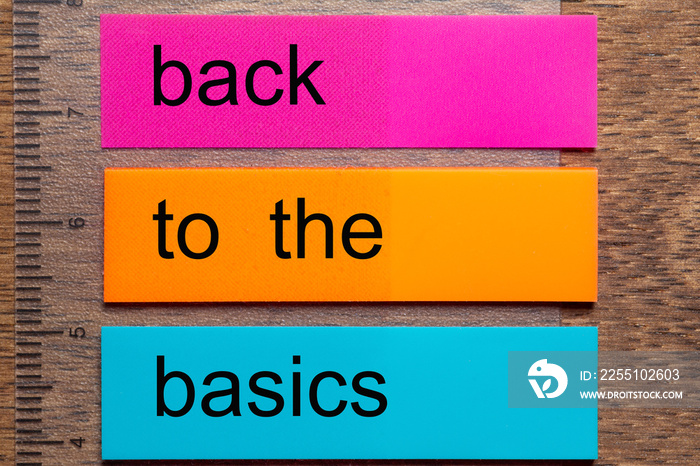 Three bookmark stickers with the phrase back to the basics on a dark natural wooden table