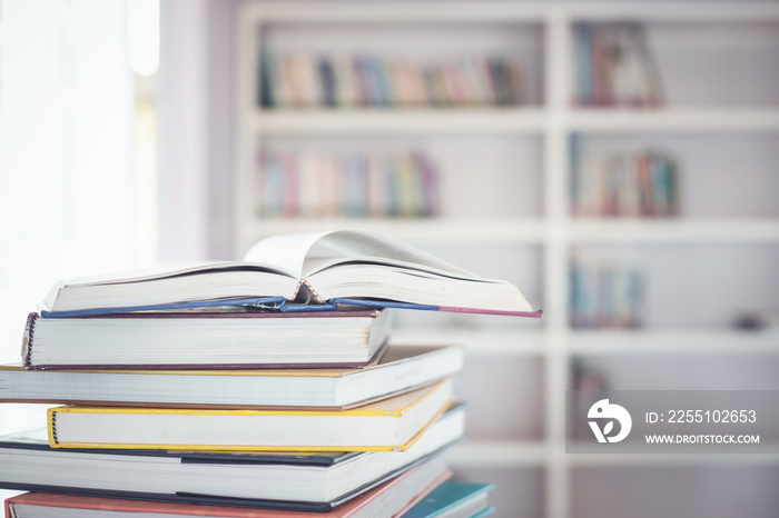 Book stack on the table in the library room and blurred space of bookshelf background