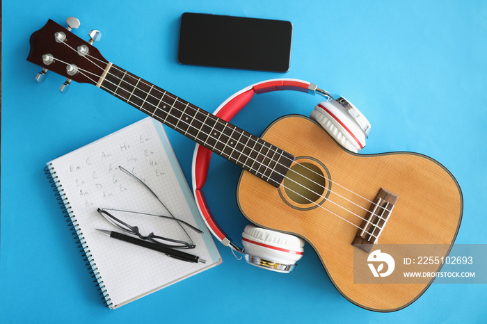 Guitar with headphones smartphones and notebook on blue background