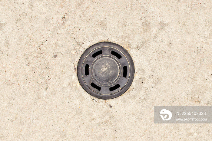 Round manhole on asphalt road. Urban sewer background. Metal drain cover texture. Minimalistic empty copy space industrial background.