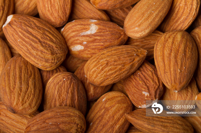 Close up on almonds resting on a flat background.