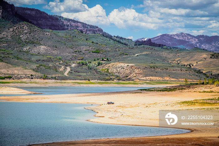 Almost dried up Blue Mesa Reservoir near Gunnison Colorado USA with pickup parked down near water and someone floating