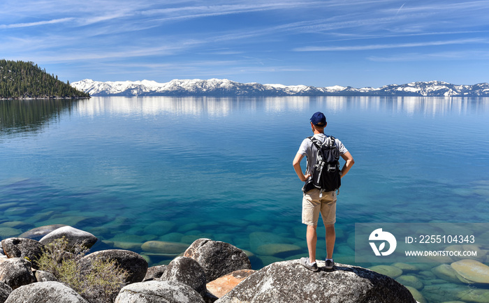 Man standing on a boulder and contemplating the Lake Tahoe, in Nevada, USA.