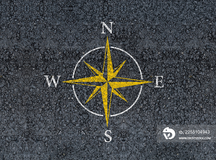 compass sign on road asphalt with east west north south