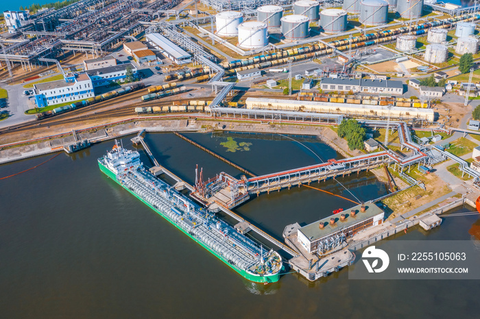 Aerial view large port with railway infrastructure for the delivery of bulk cargo by sea, loading oil using a pump station in ship tanker for transportation and delivery.