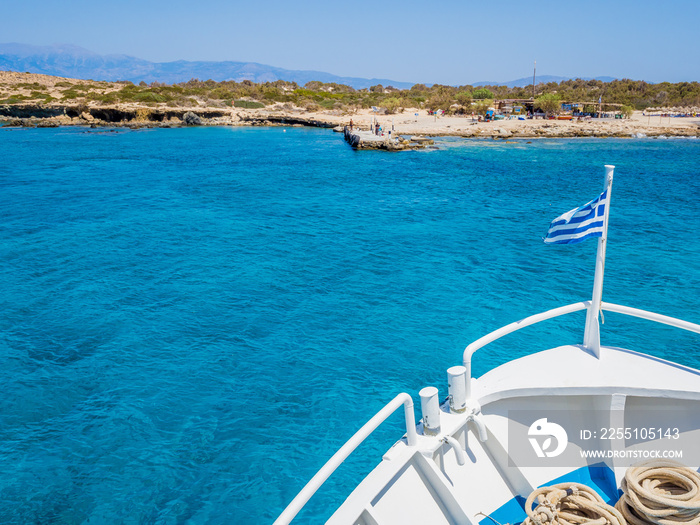 Greek flag waving on the bow of a boat sailing toward the island of Chrissi. The uninhabited island of Chrissi is available only by boat, an hour of cruise from Ierapetra, south of Crete.