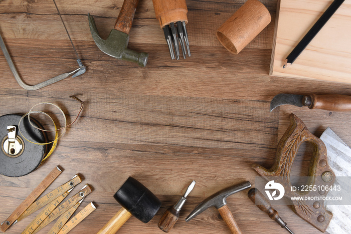 High angle closeup of a large group of tools arranged on a wood workbench around a blank space in the middle