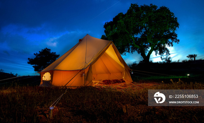 Bell tent at night against a blue hour sky