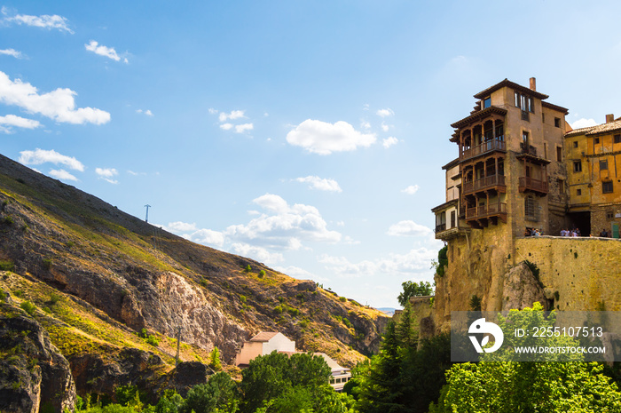 Sunny scene of the Hanged Houses (Casas Colgadas) and the mountains in the city of Cuenca, Spain. Touristic houses built on the rocks of a cliff.