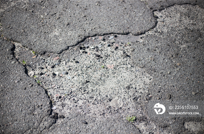 Broken asphalt and cracks on the road surface