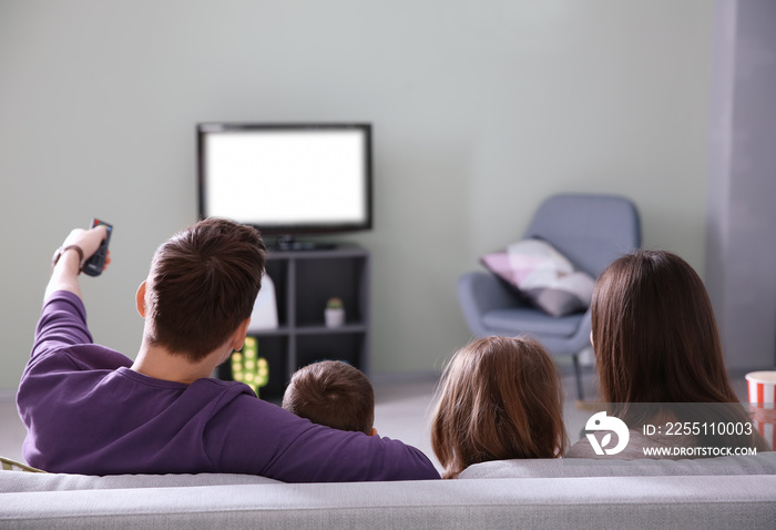 Family watching TV on sofa at home