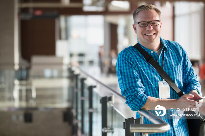 Happy man with briefcase leaning on railing.