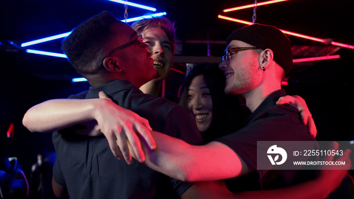 Multi-racial team of esports players tune in to the game and embrace for team spirit boost, slow motion