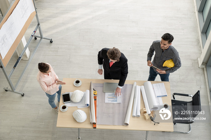 Team of male and female engineers and architects, working team, meeting, discussing construction and drawing construction plans, printing, writing on-site construction sites. Top view