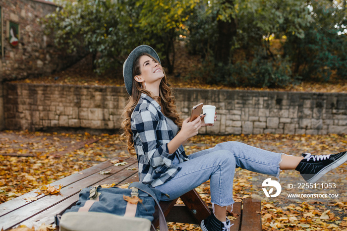 Refined white woman in stylish casual clothes spending time at countryside in autumn day. Outdoor photo of graceful lady in vintage jeans posing with happy smile in september weekend.