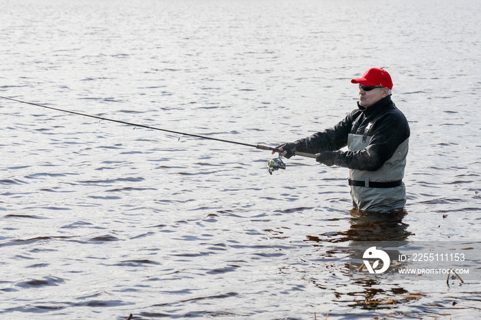 Fishermen spin fishing using chest waders to stay dry.