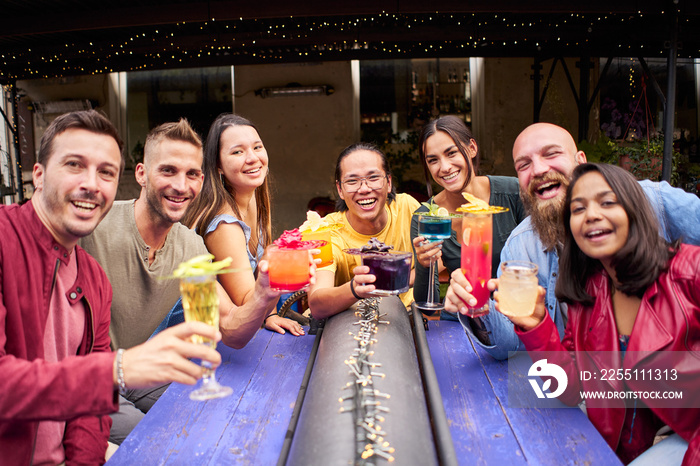 Group selfie of friends having cocktails on the terrace in a bar in summer. Fun people spending time together and having fun.