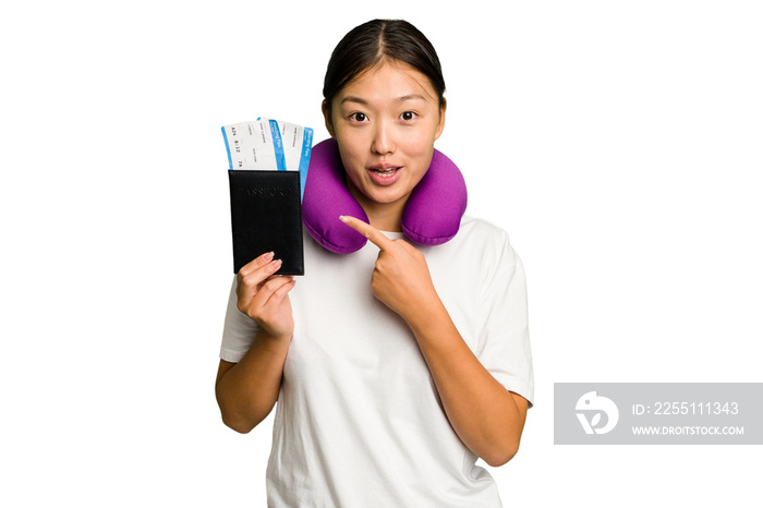 Young asian woman with inflatable travel pillow on her neck holding passport isolated pointing to the side