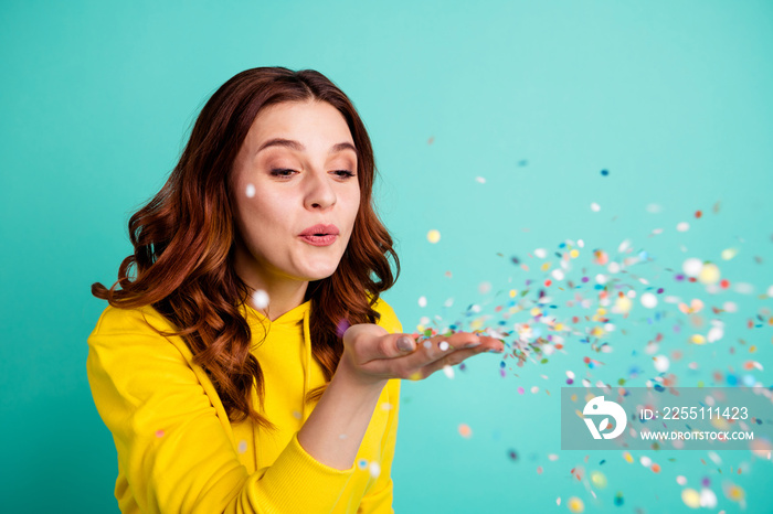 Photo of cute nice cheerful charming attractive childish youngster blowing confetti making wind isolated over teal bright color background