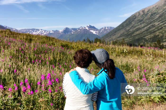 Daughter holding her mother while viewing the flowers and mountains in Alaska