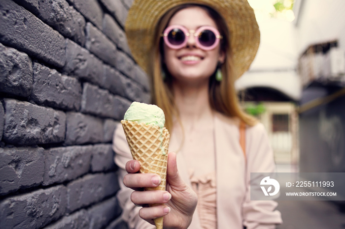 Cheerful woman in sunglasses with ice cream in hands outdoors black brick wall street style