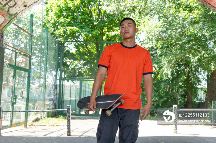 Young male skateboarder standing in park