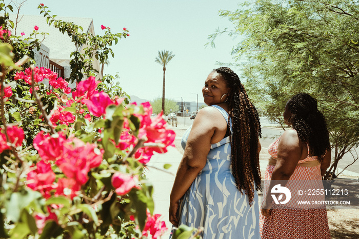 2 African American women walk away down the street one looks back