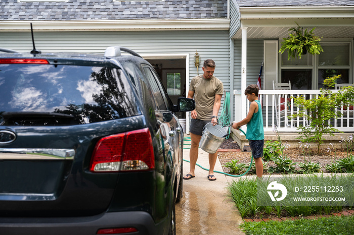 Air Force service member washes his vehicles with his sons in the driveway.