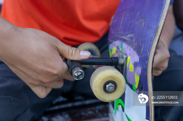 Close-up of young man fixing skateboard