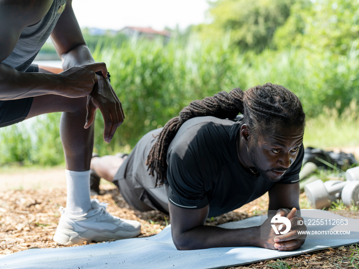 Man exercising with personal trainer doing plank