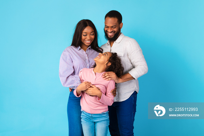 African American man hugging his wife and smiling daughter