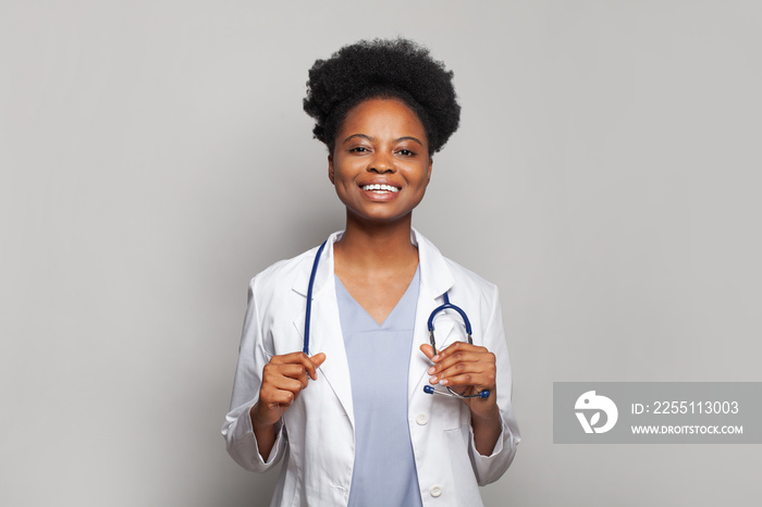 Friendly woman doctor wearing white coat with stethoscope looking at camera and smiling cheerfully