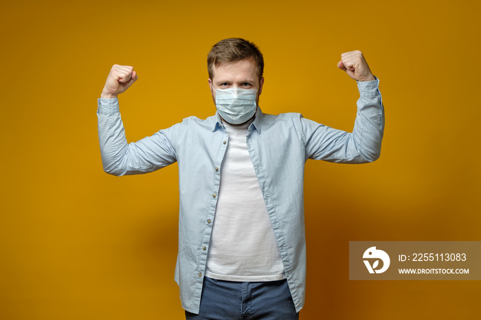 Satisfied man put on a medical mask on face and feels protected from viruses, showing a gesture of confidence with hands.