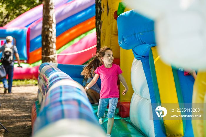 Happy little girl having lots of fun on a jumping castle during sliding.