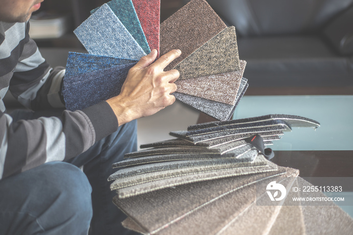 Man choosing the right colour and material of carpet for his new apartment in floor studio, furnishing households