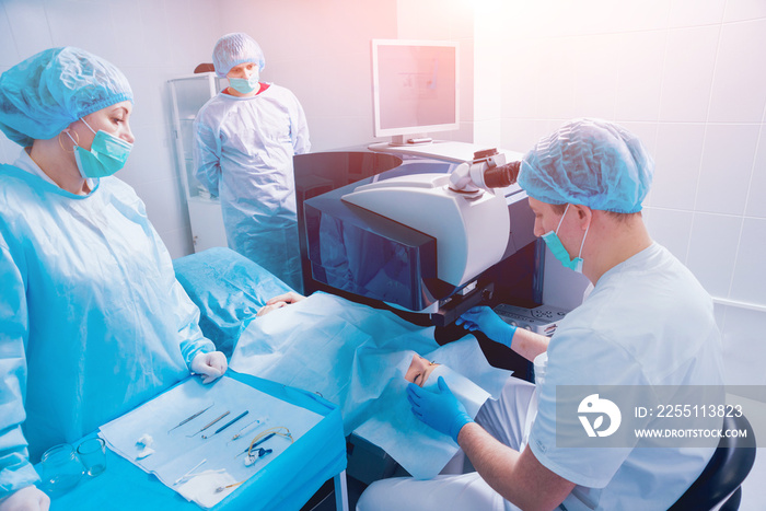 Laser vision correction. A patient and team of surgeons in the operating room during ophthalmic surgery. Eyelid speculum. Lasik treatment.