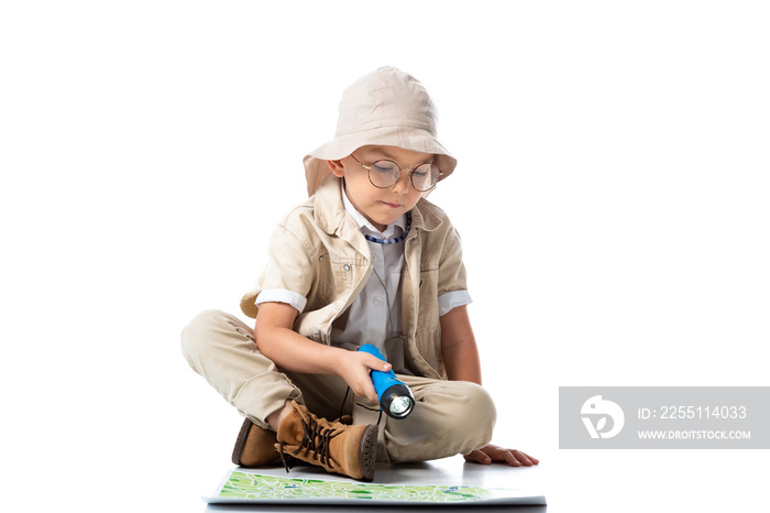 explorer child in hat and glasses holding flashlight and looking at map on white