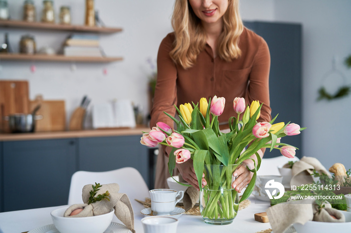 Caucasian woman putting vase with fresh tulips on the table