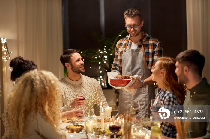 holidays, celebration and people concept - happy smiling friends having christmas dinner at home in evening