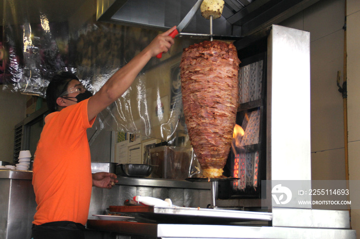 Latino taquero man working with protection mask, typical mexican food tacos al pastor, new normal covid-19