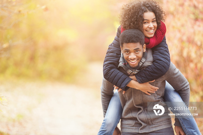 Afro couple in autumn park having fun, copy space